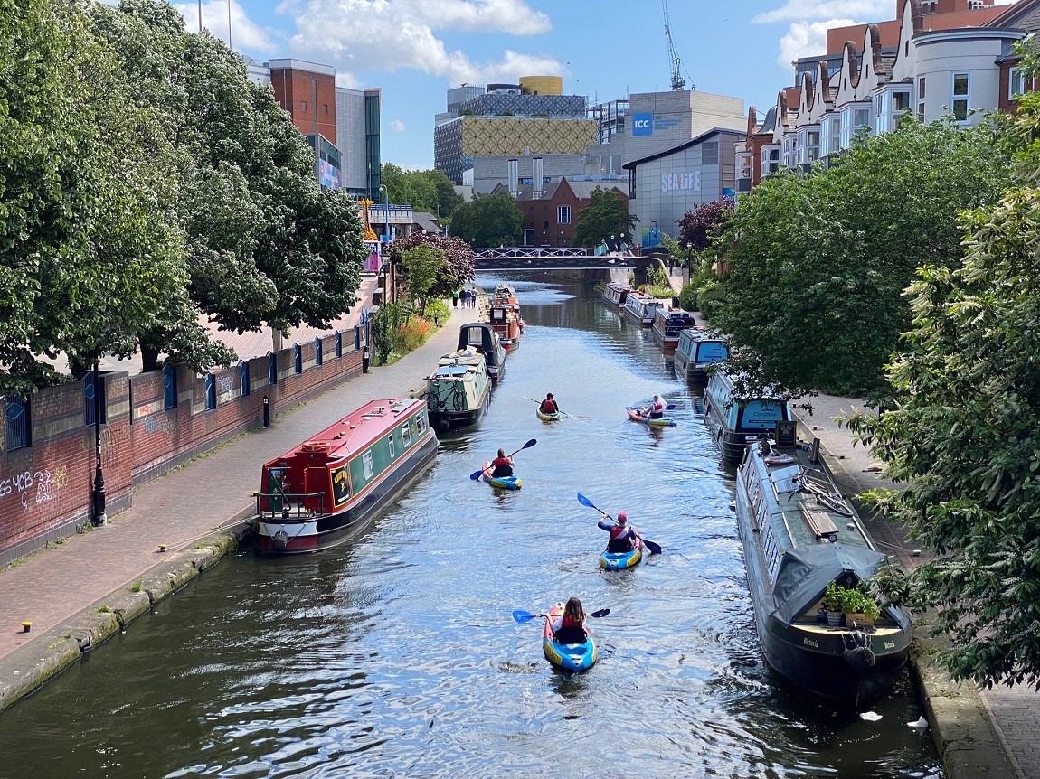 An aerial view of the Birmingham skyline and people kayaking along the canal  