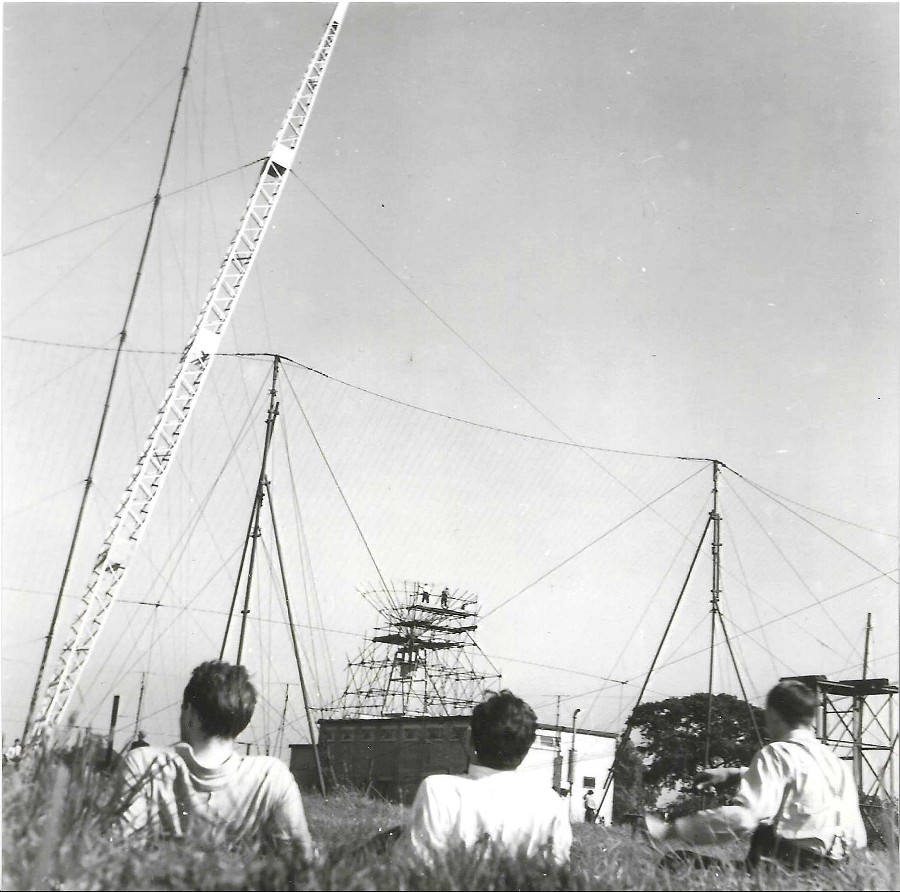 Three people lie down outside with semi constructed building in background