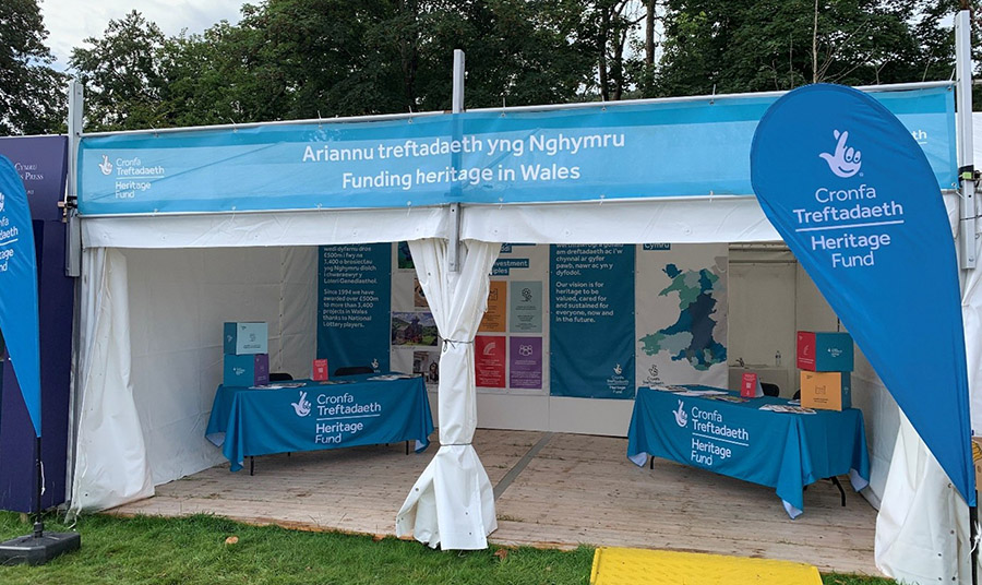 An outdoor booth containing Heritage Fund branded stalls and banners
