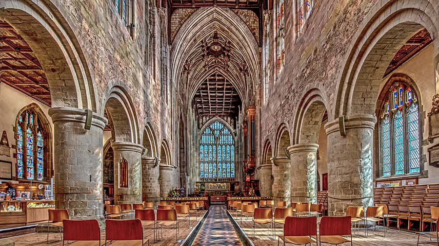 Interior of Great Malvern Priory with wide pillars, arches and stained glass windows