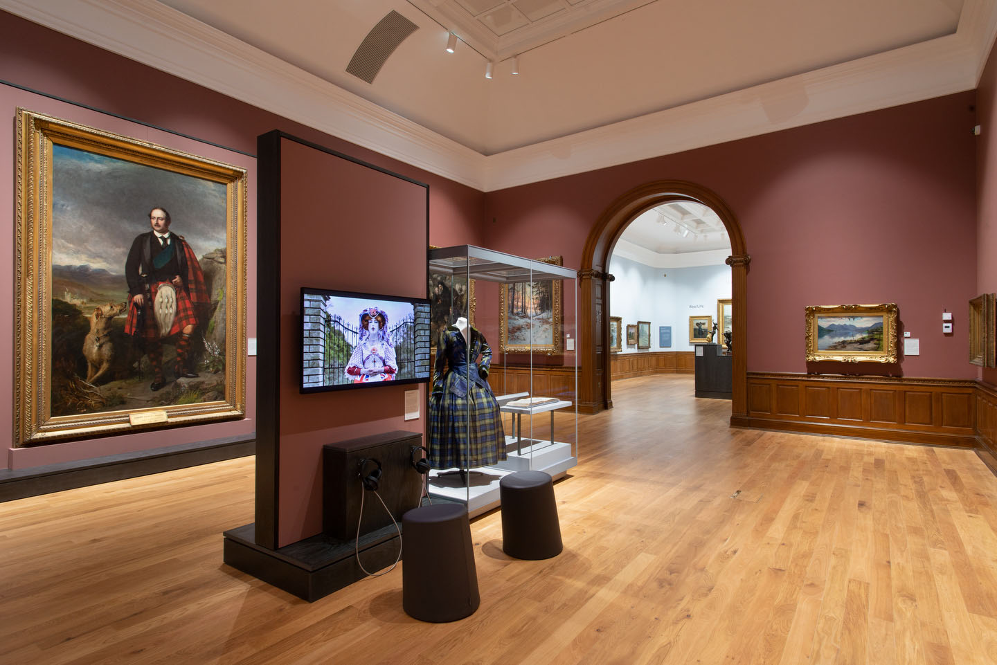 View through a gallery with paintings, TV screen and arch