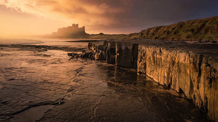 Shot of castle in the distance at sunset with cliffs and sea