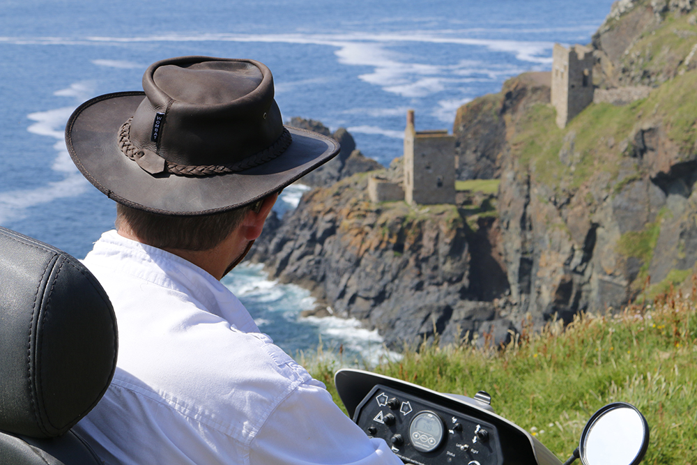 Man using tramper looking out at building on cliff edge 