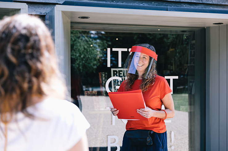 A young woman wearing a face shield and carrying a folder