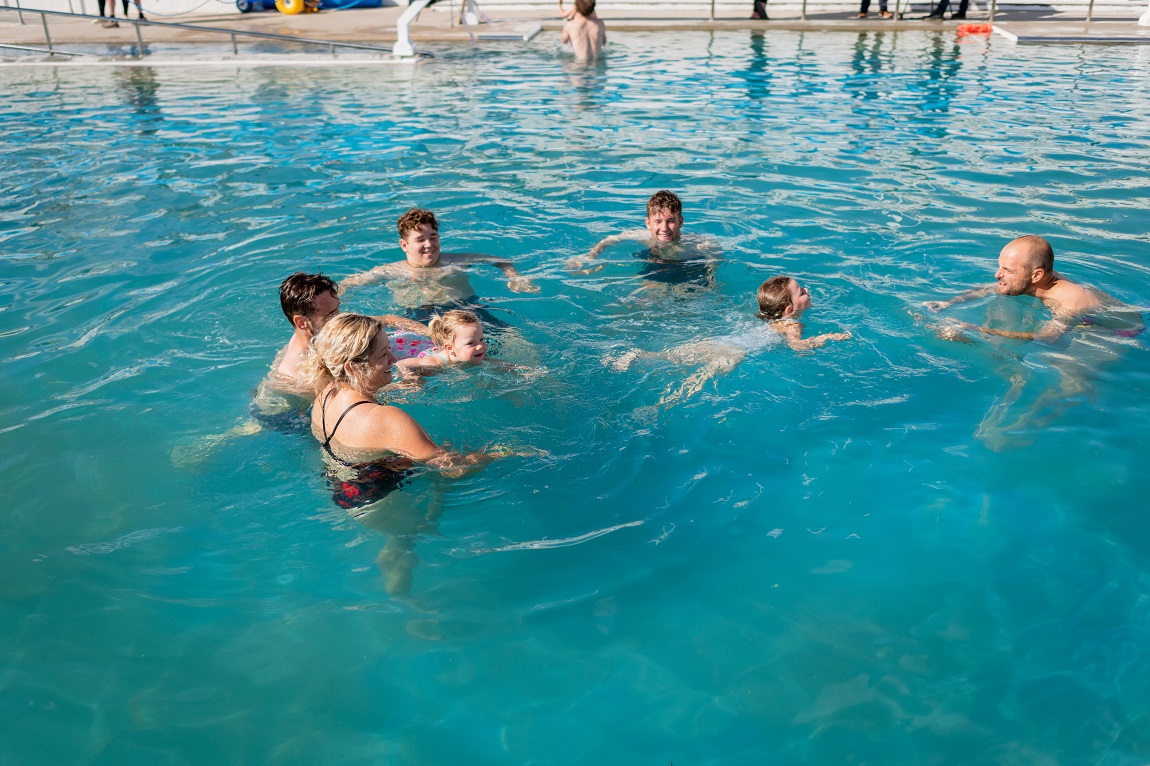 People swimming and playing with children in the geothermal pool
