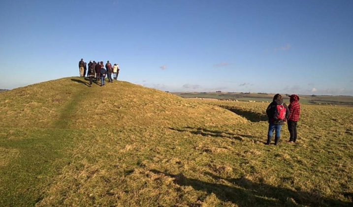 Human Henge participants stand on the top of a hill in bright weather 