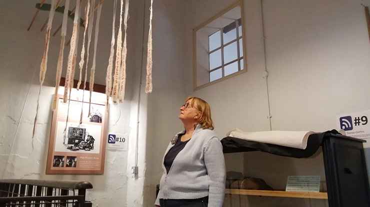 A woman looks up at thin strips of paper that are hanging from the ceiling