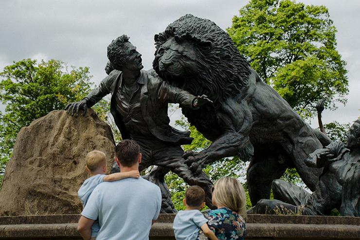 Adult and child observing a sculpture of a man being attacked by a lion