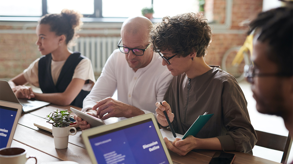 People referring to computer and tablet in meeting