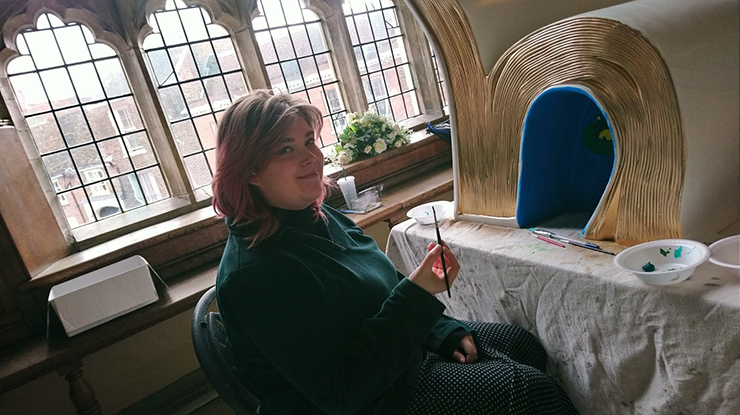 A person rests from painting an exhibit that resembles a giant book