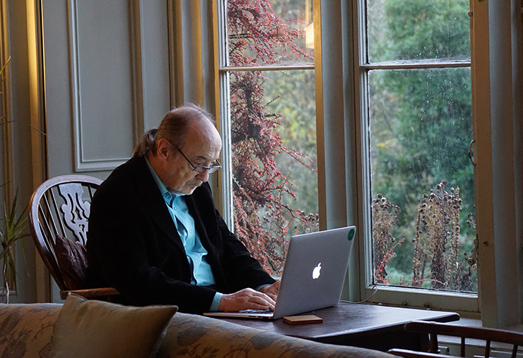 Older man working on a laptop in a window