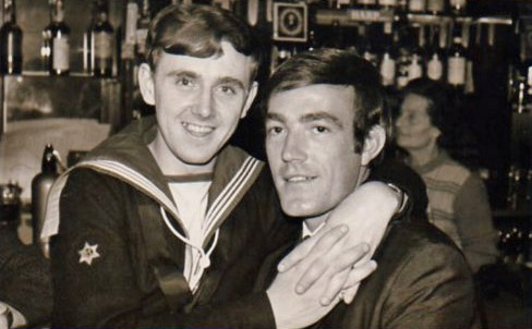 Archive photo of a sailor and another man embracing in a pub