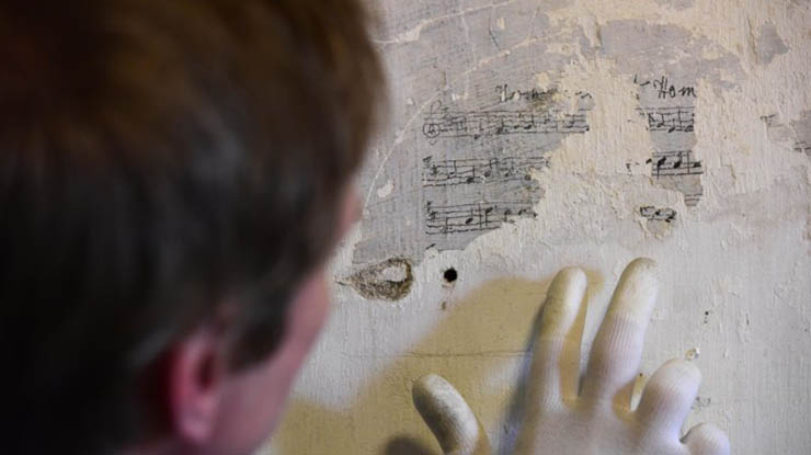 A person looking at scuffed musical notes on a wall