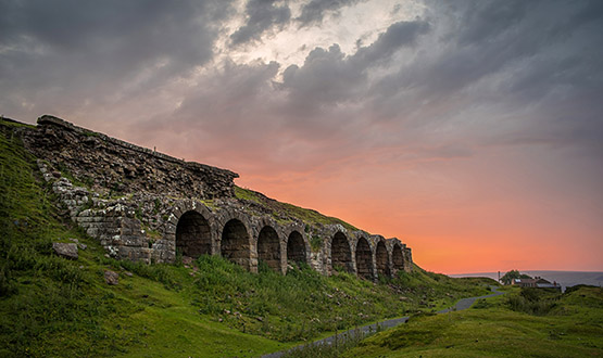 A row of stone chambers in a hillside at sunset