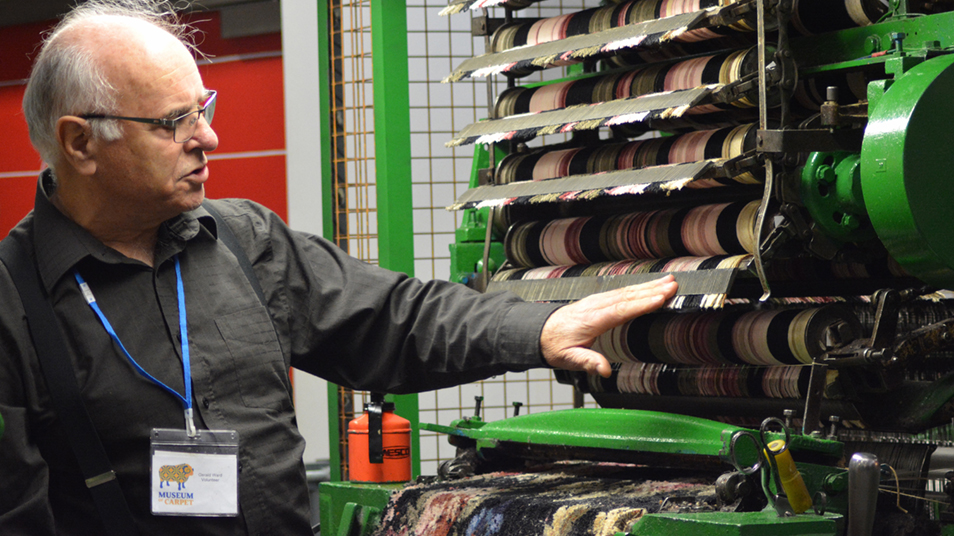 A man showing a machine at the Museum of Carpet