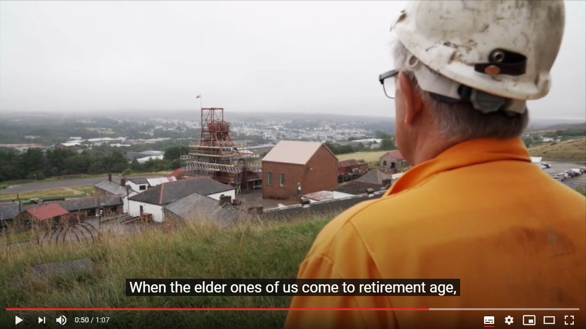 Video still of miner, including subtitle: "When the elder ones of us come to retirement age". 
