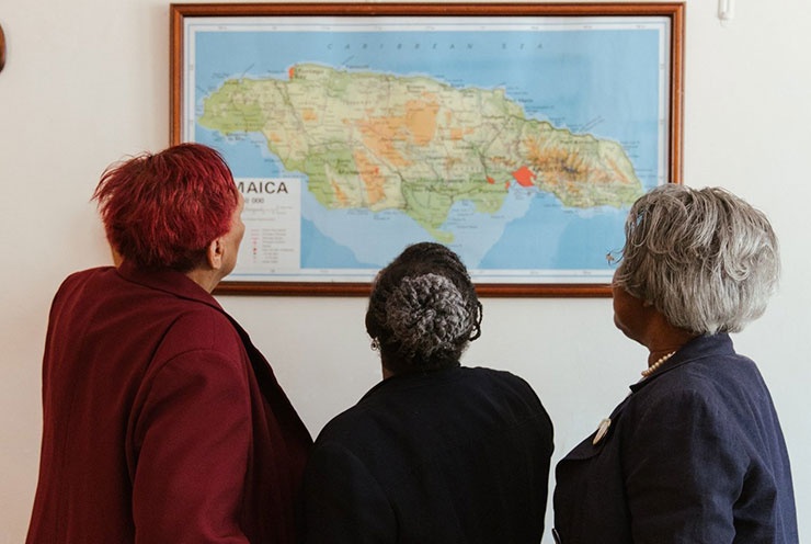Three women looking at a map of Jamaica at the exhibition from Jamaica Society Leeds