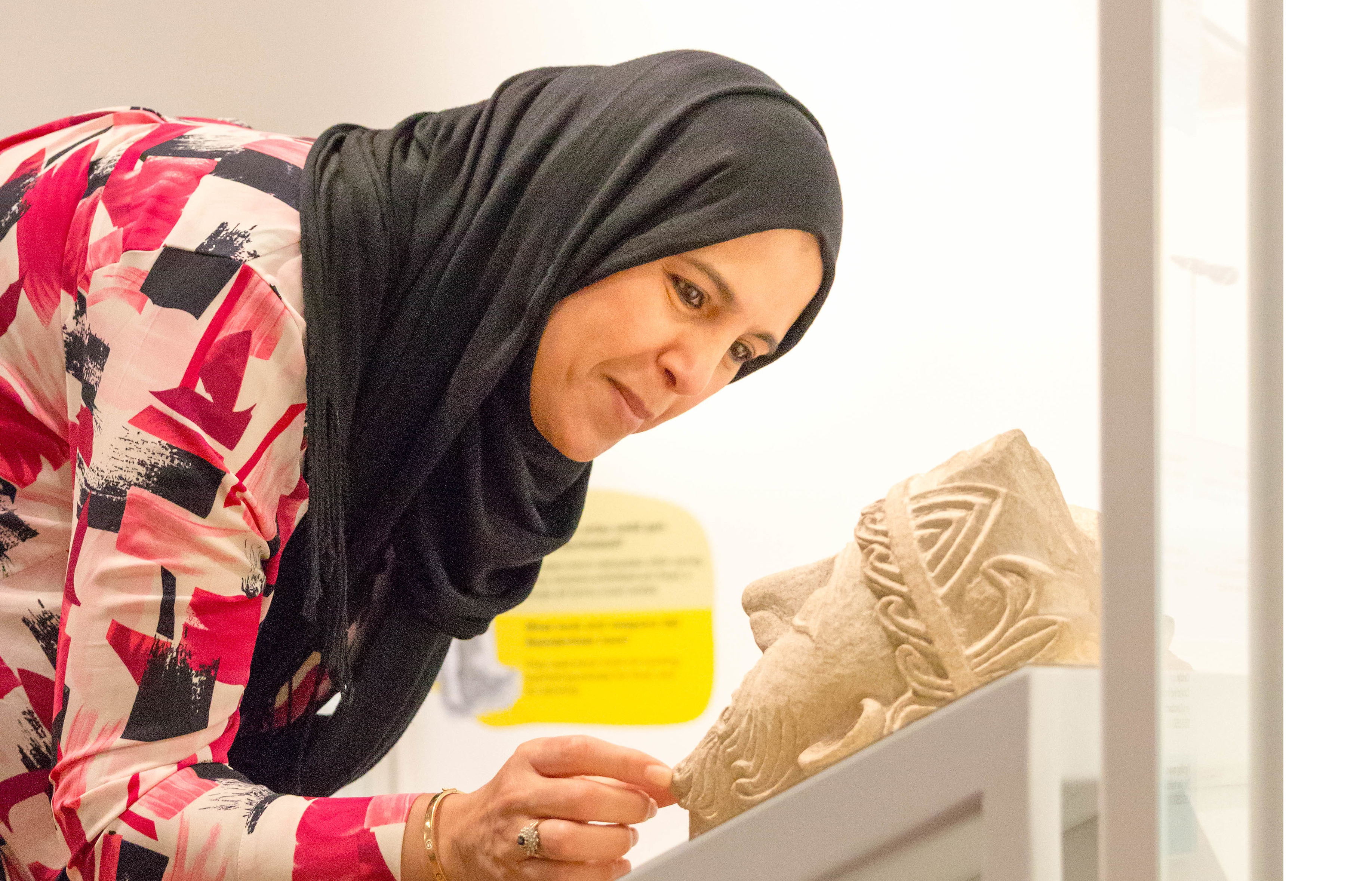 A woman looks at a stone head