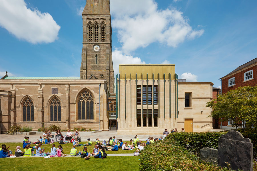 A group of school children sitting on the grass outside Leicester Cathedral