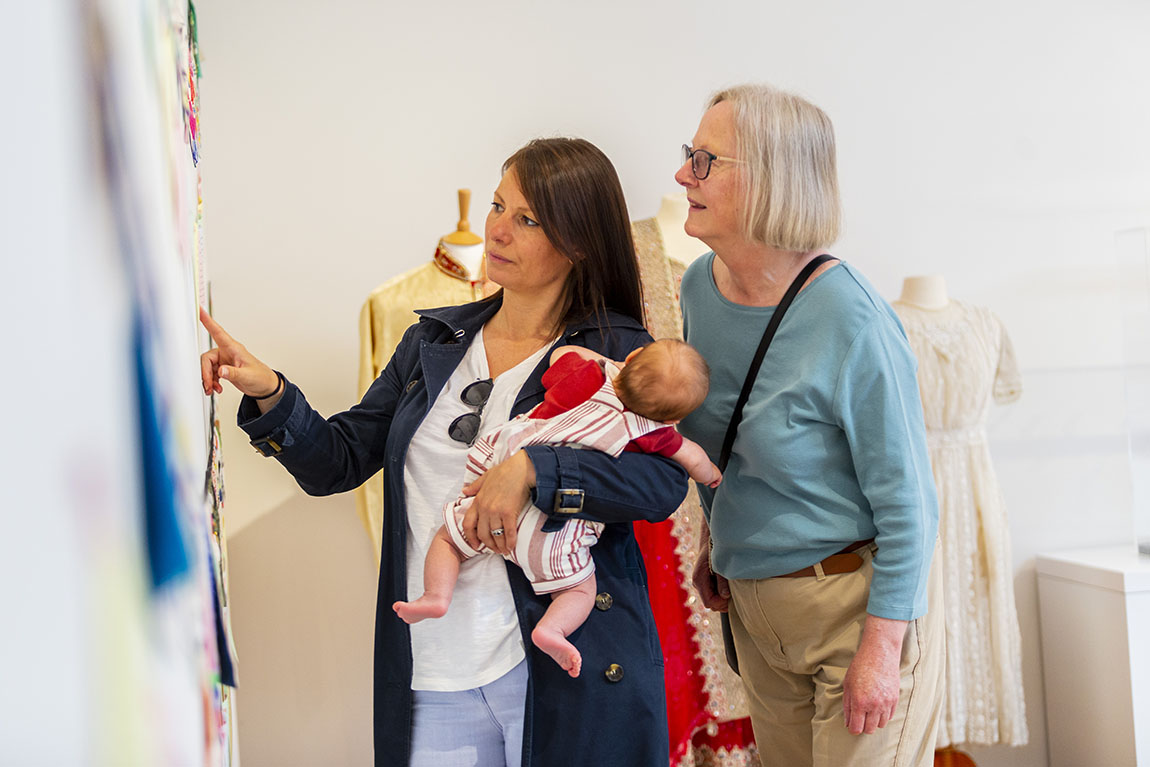 Two women and a baby look at museum display