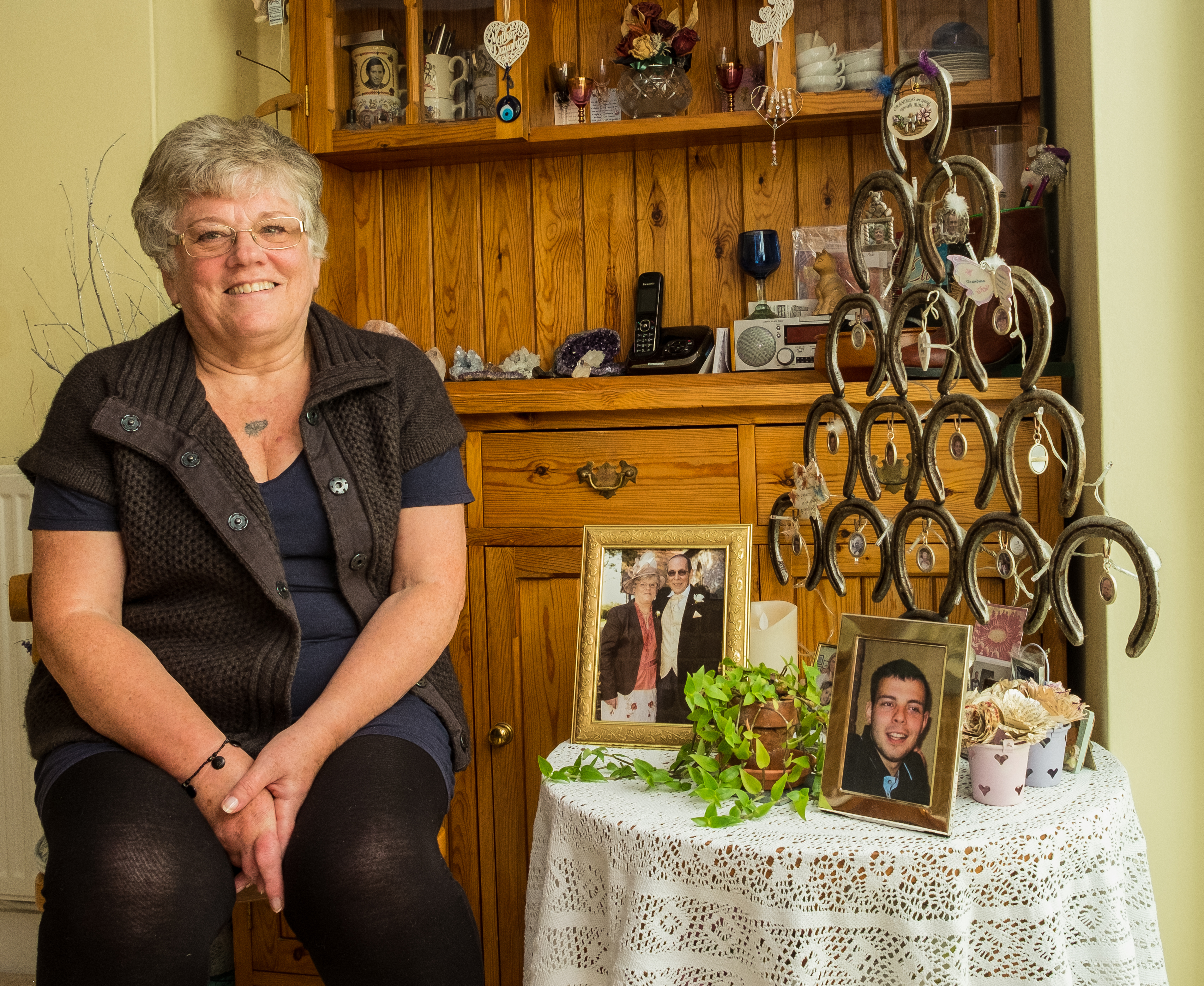Changing lives: how art helped Angela through bereavement Angela sits in her home, with photos of her late husband and grandson
