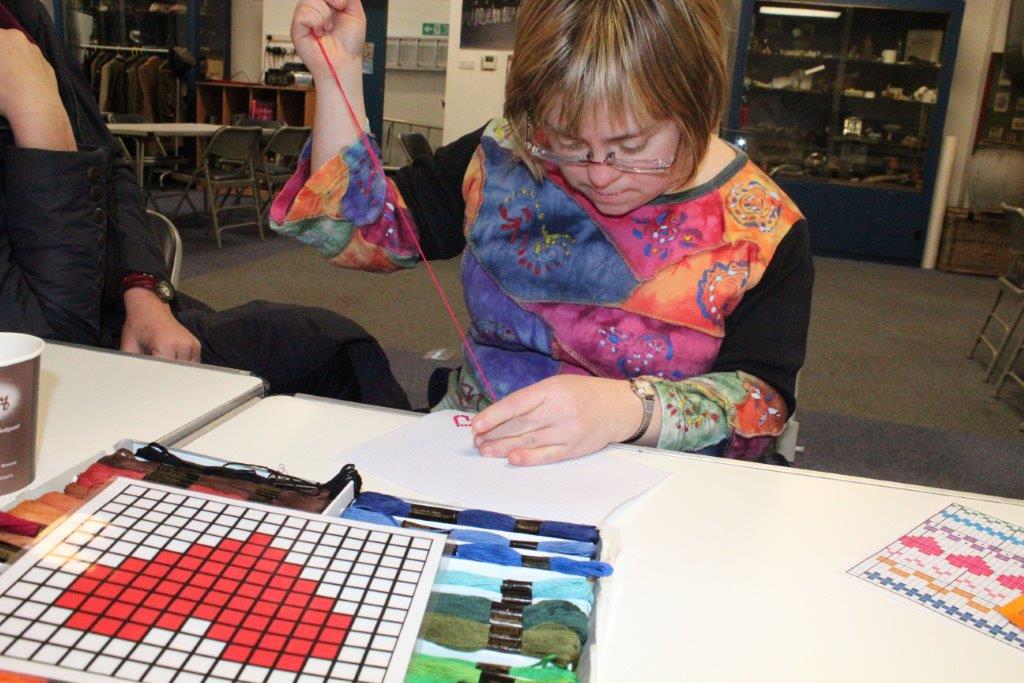 All-inclusive heritage adventures Sara, Mencap oral historian, trying cross stitching