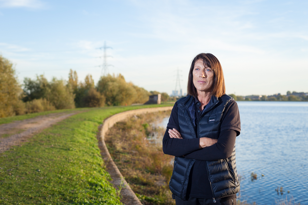 A woman stands in front of a reservoir