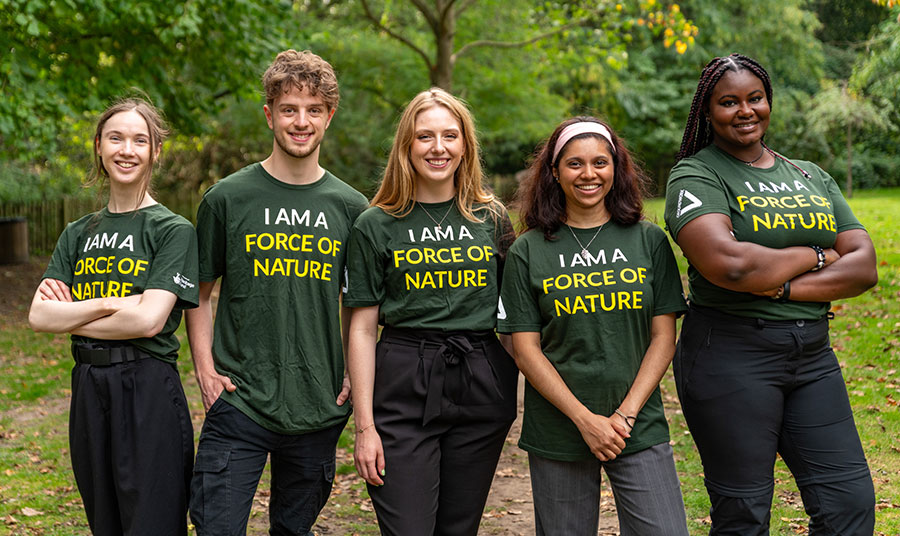 Five young adults standing in a park wearing matching T-shirts that say I am a force of nature