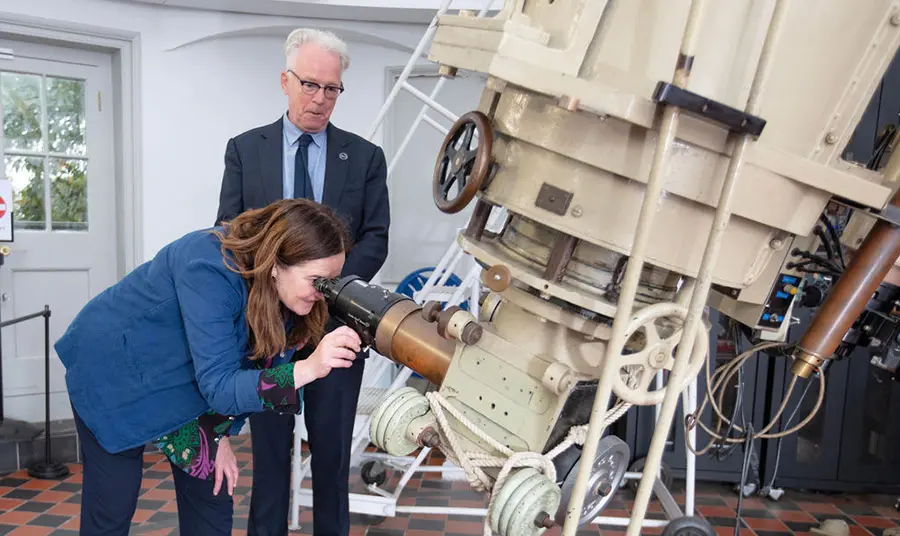 Two people looking through a large telescope