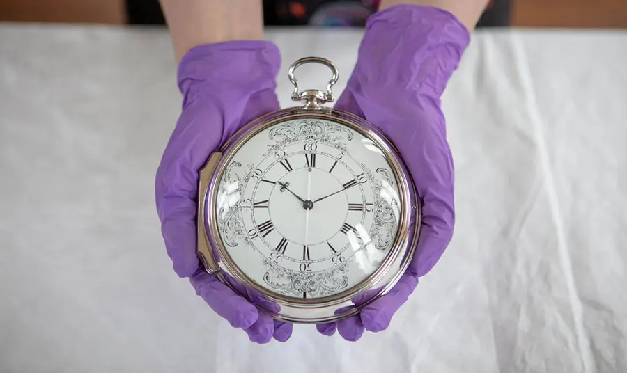 Gloved hands holding a clock