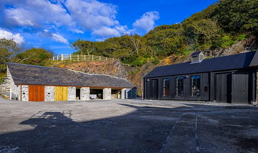 A new building with black cladding next to older stone buildings