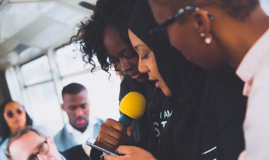 Young people reading poetry around a microphone