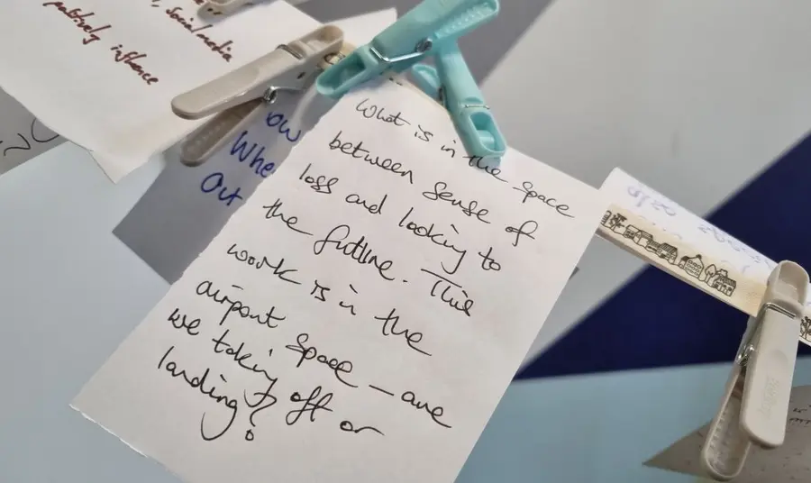 Cards carrying notes, ideas and questions are pegged to a washing line during a felt experience workshop.