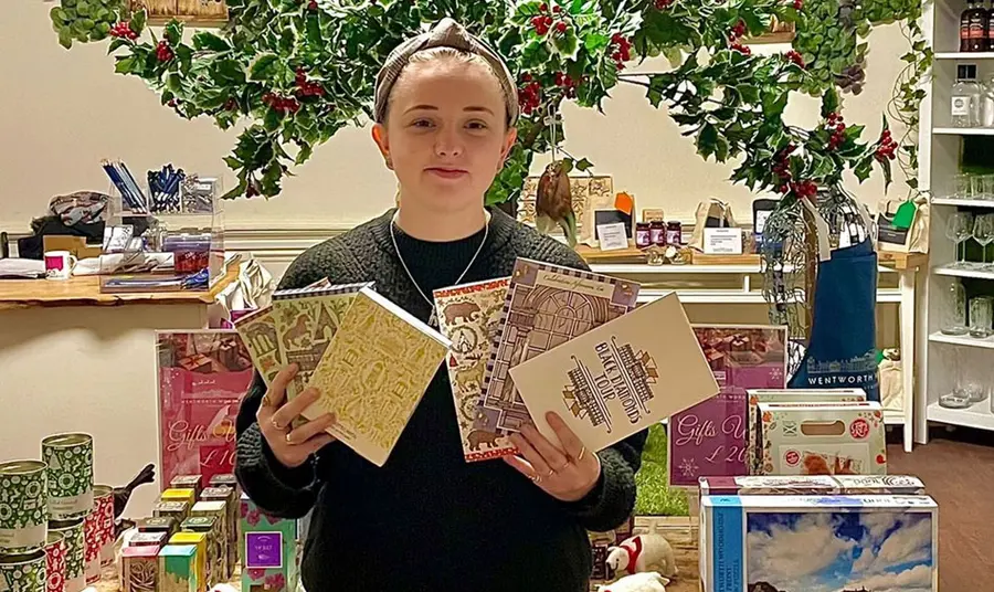 A young woman holding a collection of books in a festive-decorated shop