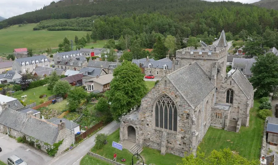 An aerial view of St. Margaret's Church in Braemar. A drone photograph of the church of St. Margaret's, nestled between houses and lush green fields.
