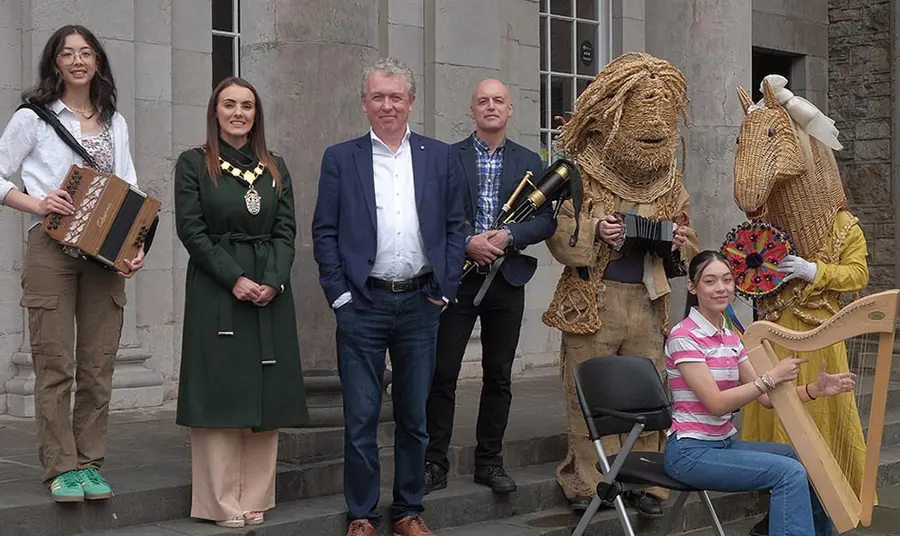 a group of people including a local leader, people with a harp, an accordion and pipes and two people in traditional costumes