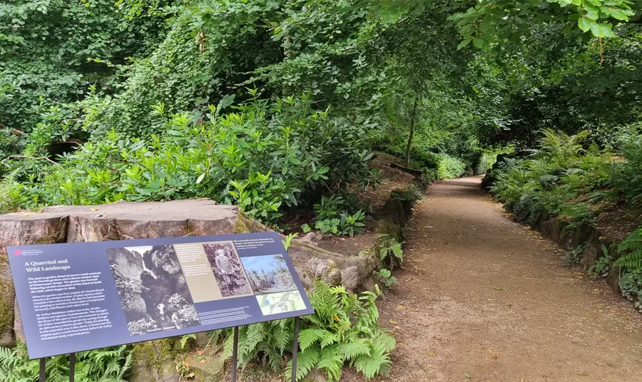 A path running through Belsay gardens with a sign telling visitors about the plants