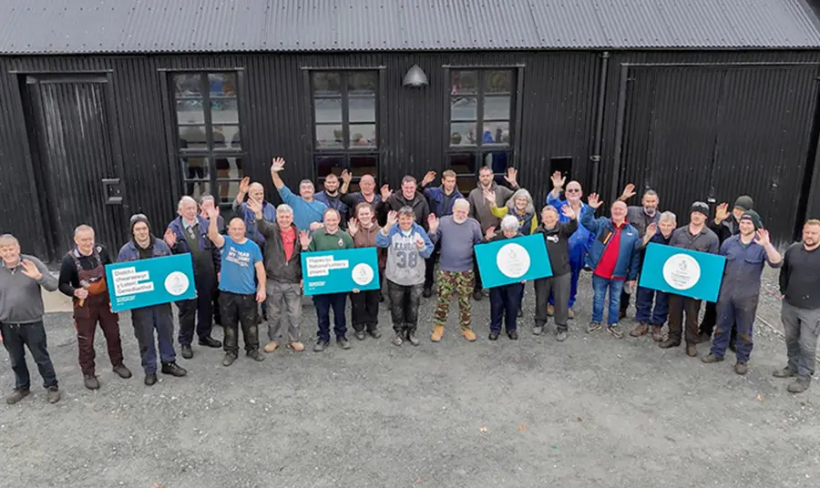 A large group of people waving and posing with signs thanking National Lottery players