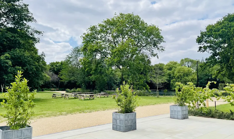 New picnic benches on the lawn in front of Boston Manor House looking onto the lake