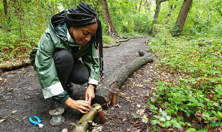 A black woman works on a forest path