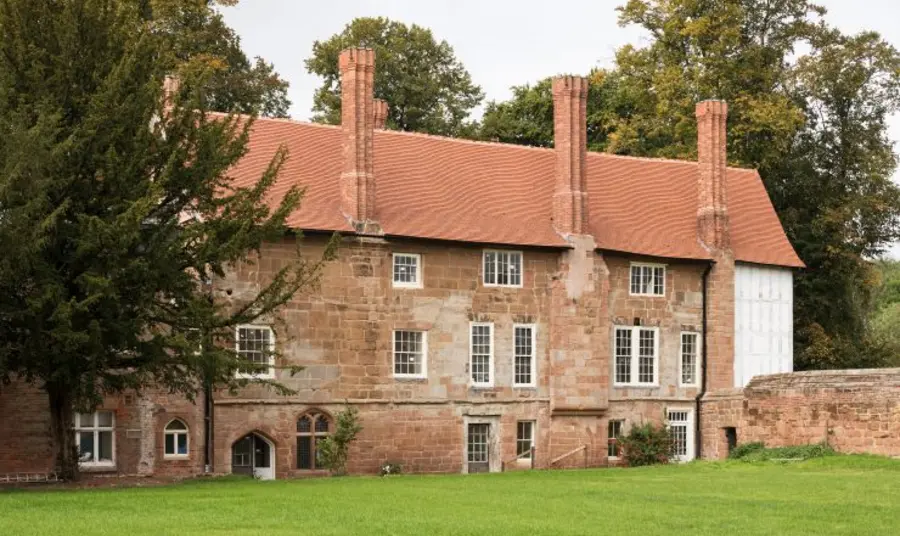 The exterior of Charterhouse in Coventry, a red sandstone building with many chimneys and windows