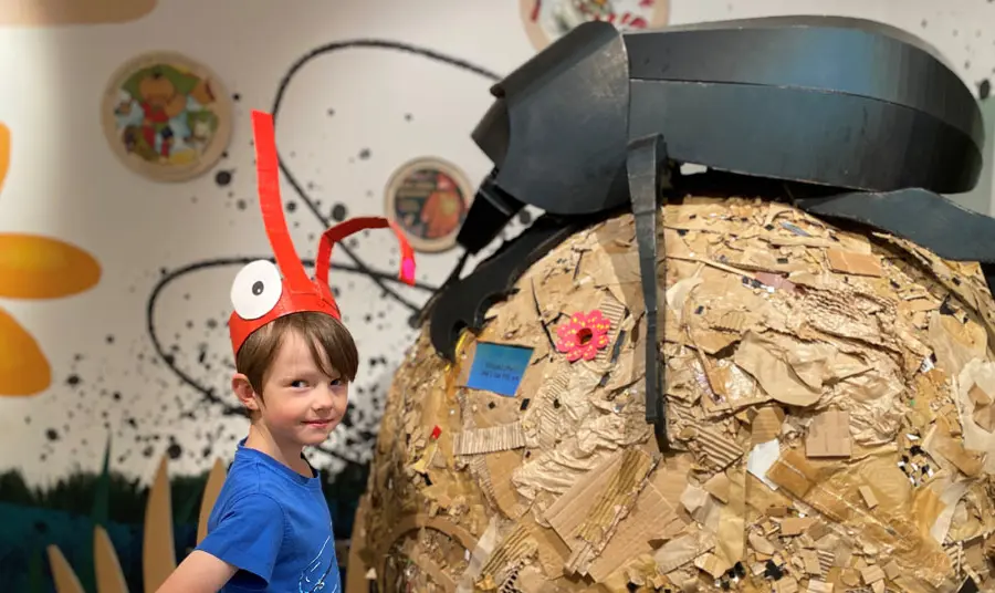 Child stand in front of a giant model of a dung beetle