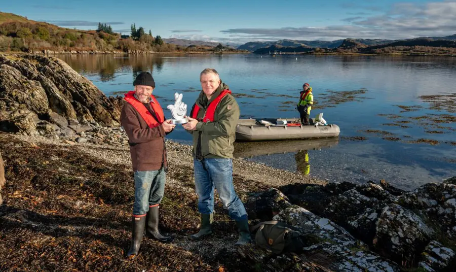 Danny stands on the shores of the loch receiving the award from Ray Mears