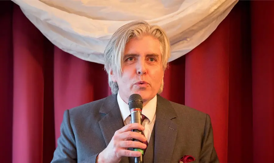 David Hevey speaks into a microphone at an event