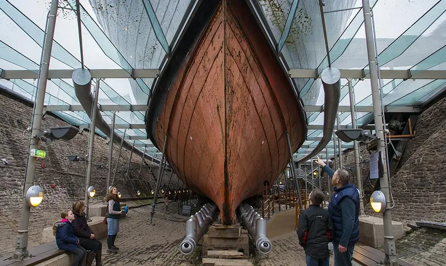 Pobl yn edrych i fyny ar gragen SS Great Britain o'r tu mewn i'r doc sych