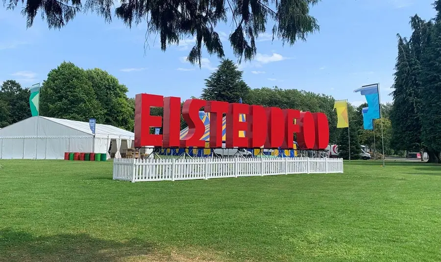 Large red letters spelling ‘Eisteddfod’ in front of tents in a field