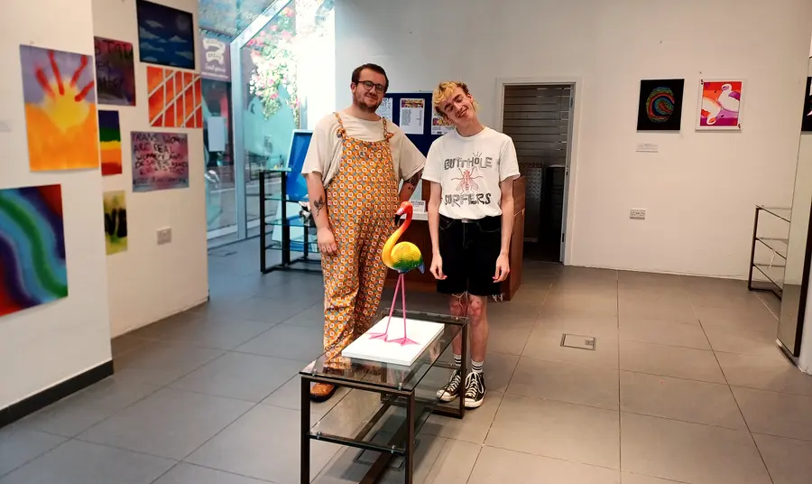 Participants at the I Me Us exhibition Two people standing in the middle of an art exhibition