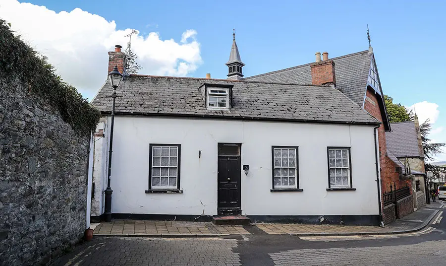 Sexton's Cottage, a small white 19th-century cottage with black accents