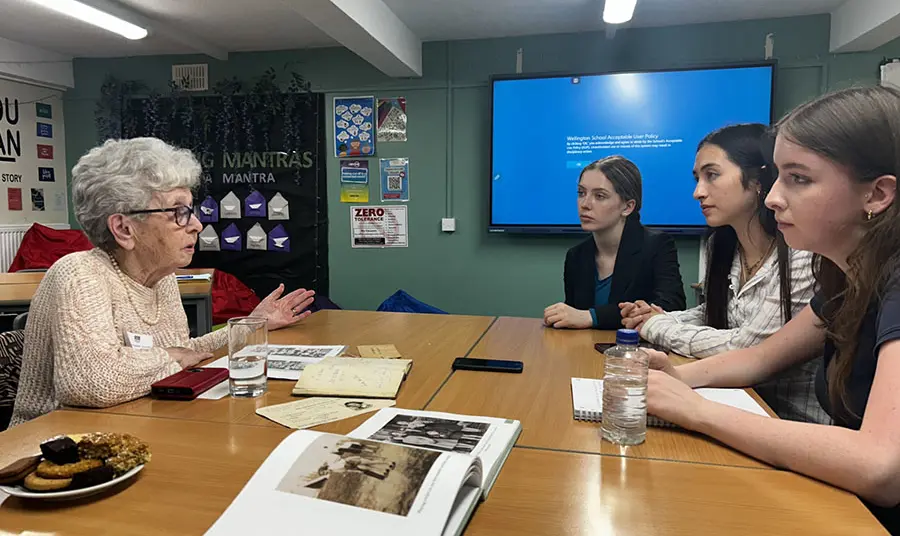A Holocaust survivors speak with young people inside a school.