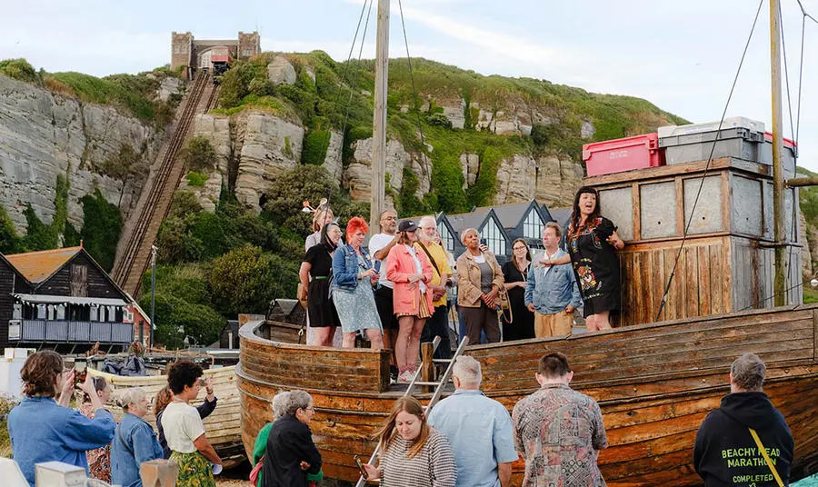 A group of people standing on the deck of a small wooden boat